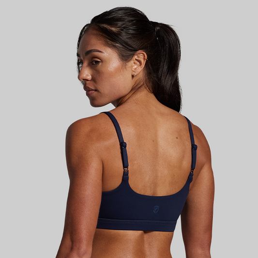 Woman wearing a navy sports bra on a gray background