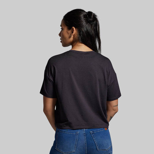 Person wearing a black t-shirt and blue jeans on a gray background