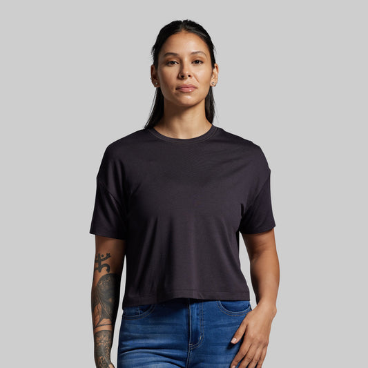 Person wearing a black t-shirt and blue jeans against a gray background