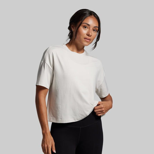 Woman wearing a white t-shirt and black leggings against a gray background
