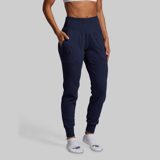 Person wearing navy jogger pants on a gray background