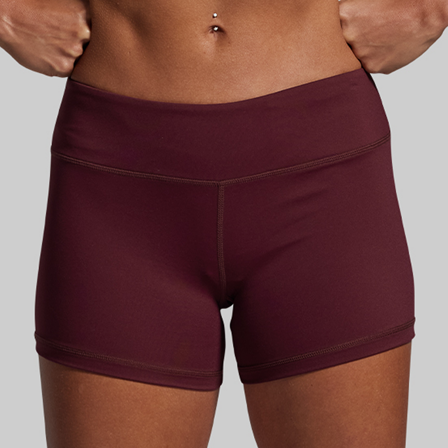 Maroon athletic shorts worn by a person on a gray background