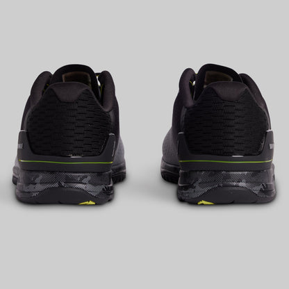 Black athletic shoes with green accents on a light gray background