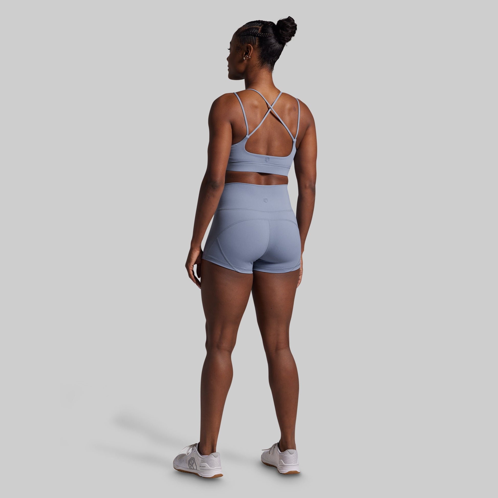 Woman wearing a light blue sports bra and shorts set on a gray background