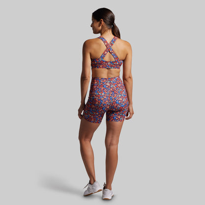 Woman wearing a patterned sports bra and shorts on a gray background