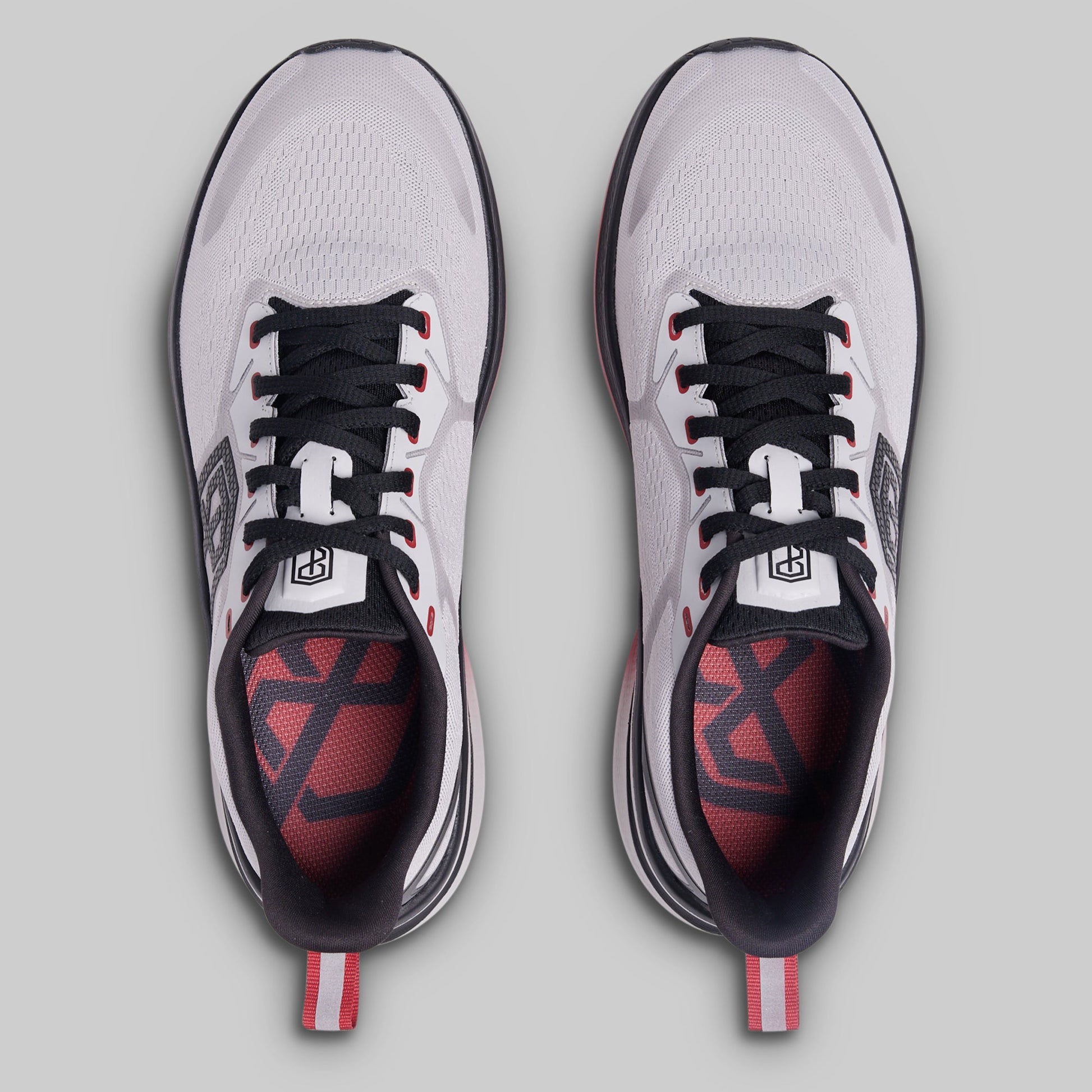 Pair of white athletic shoes with black and red accents on a gray background