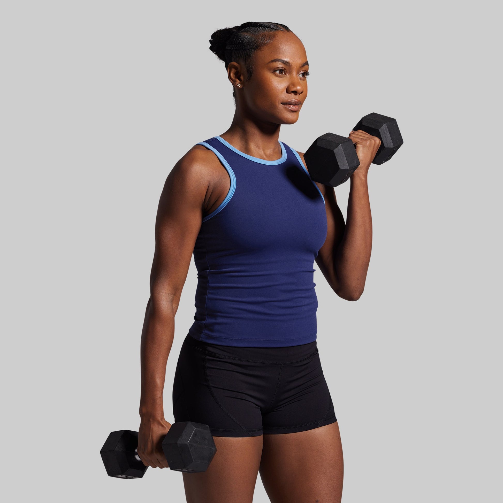 Woman holding two dumbbells against a gray background