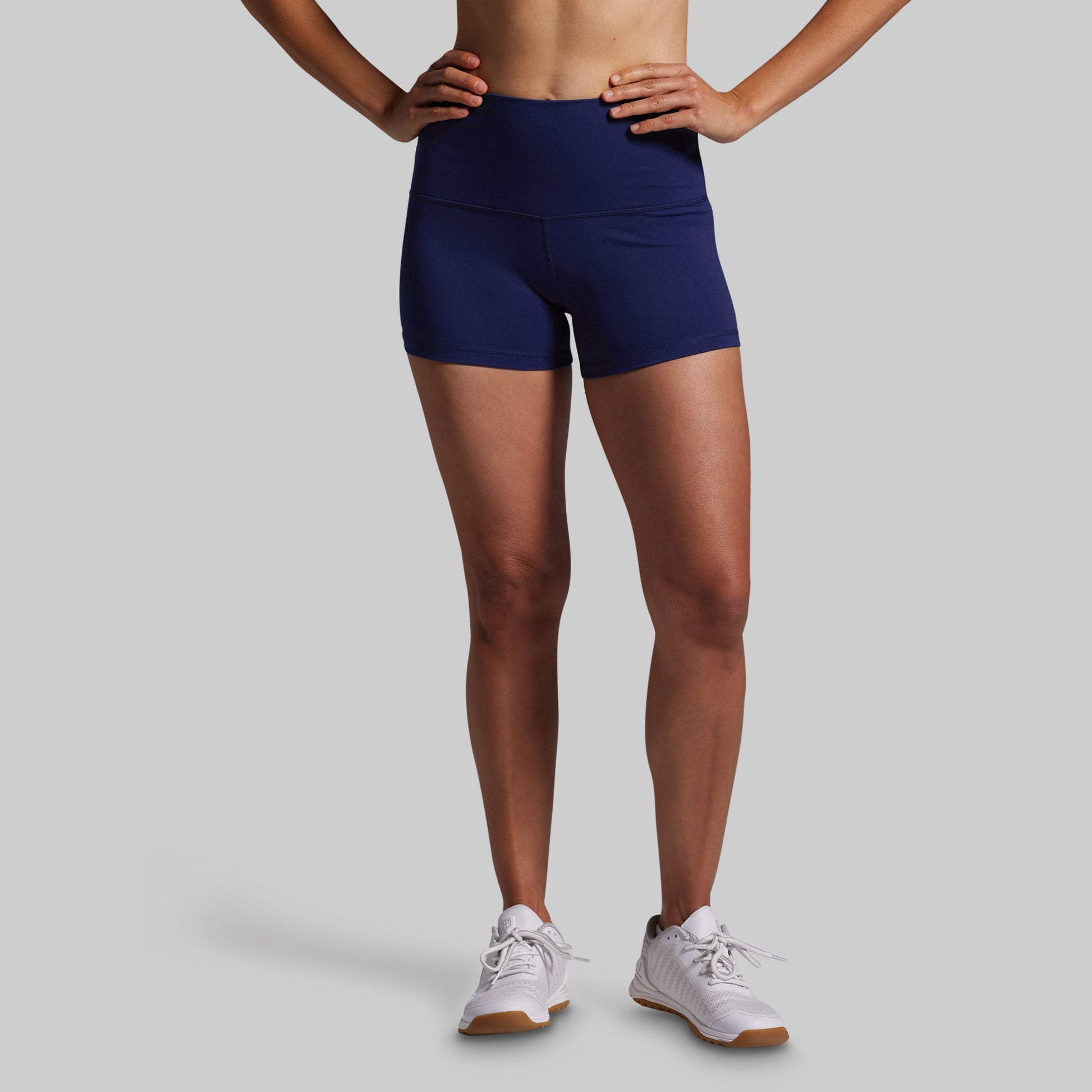Person wearing navy blue athletic shorts on a gray background