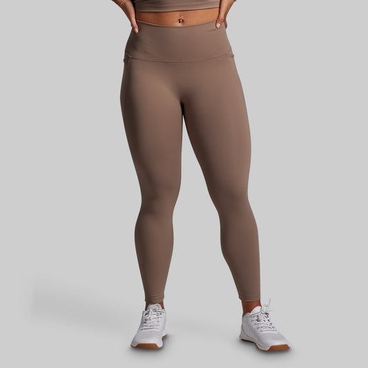 Person wearing brown leggings on a gray background