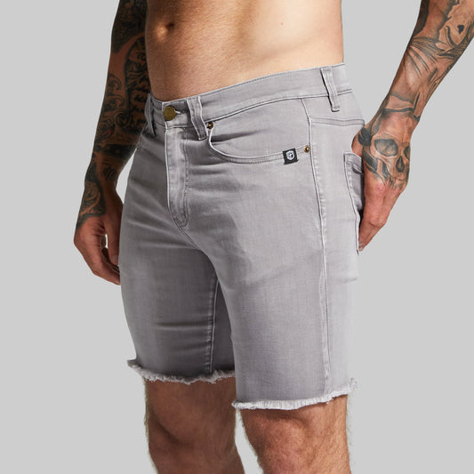 Gray denim shorts worn by a person with tattoos on a plain background