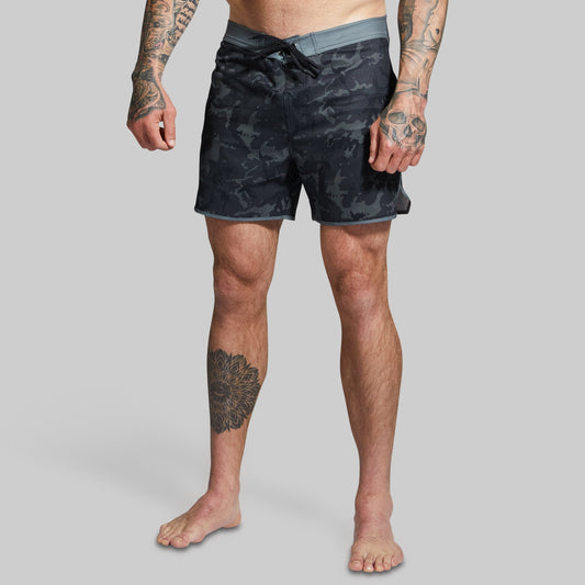 Person wearing black camouflage shorts on a gray background