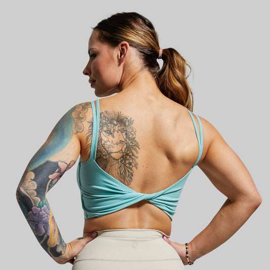 Woman wearing a turquoise sports bra with a gray background