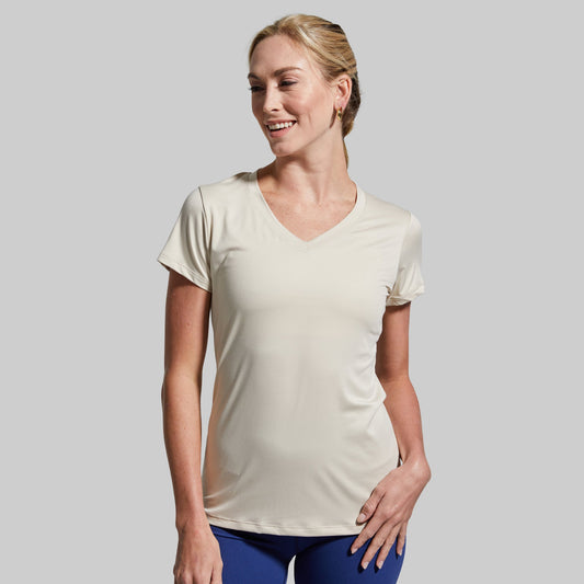 Woman wearing a beige t-shirt and blue leggings on a gray background