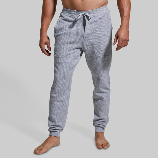 Person wearing gray textured jogger pants on a plain background