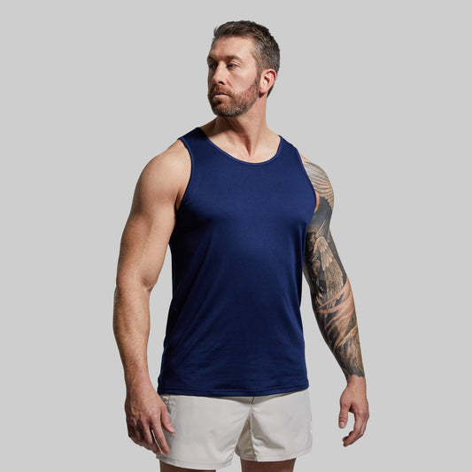 Man wearing a navy tank top and white shorts against a gray background
