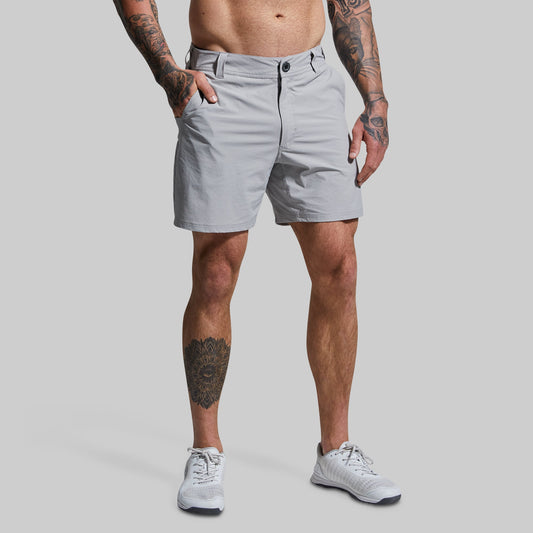 A male model wearing gray Traverse Shorts and white sneakers. The shorts are short-cut, falling above the knee, in a solid grey color.