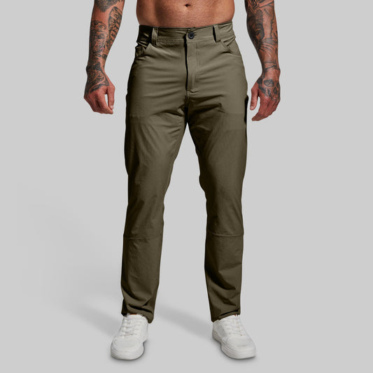 A male model wearing a pair of green Traverse Pants with a button-and-fly closure, belt loops, and standing upright.