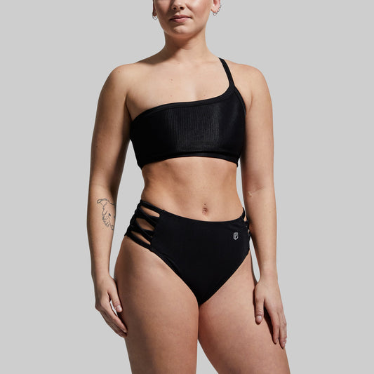 Person wearing a black bikini against a plain background