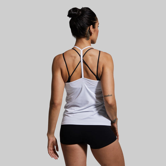 Woman wearing a white tank top with racerback design and black shorts on a gray background