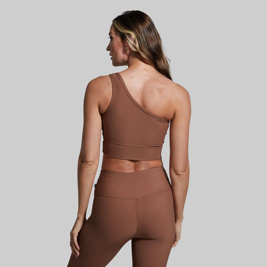 Woman wearing a brown ribbed sports bra against a plain background